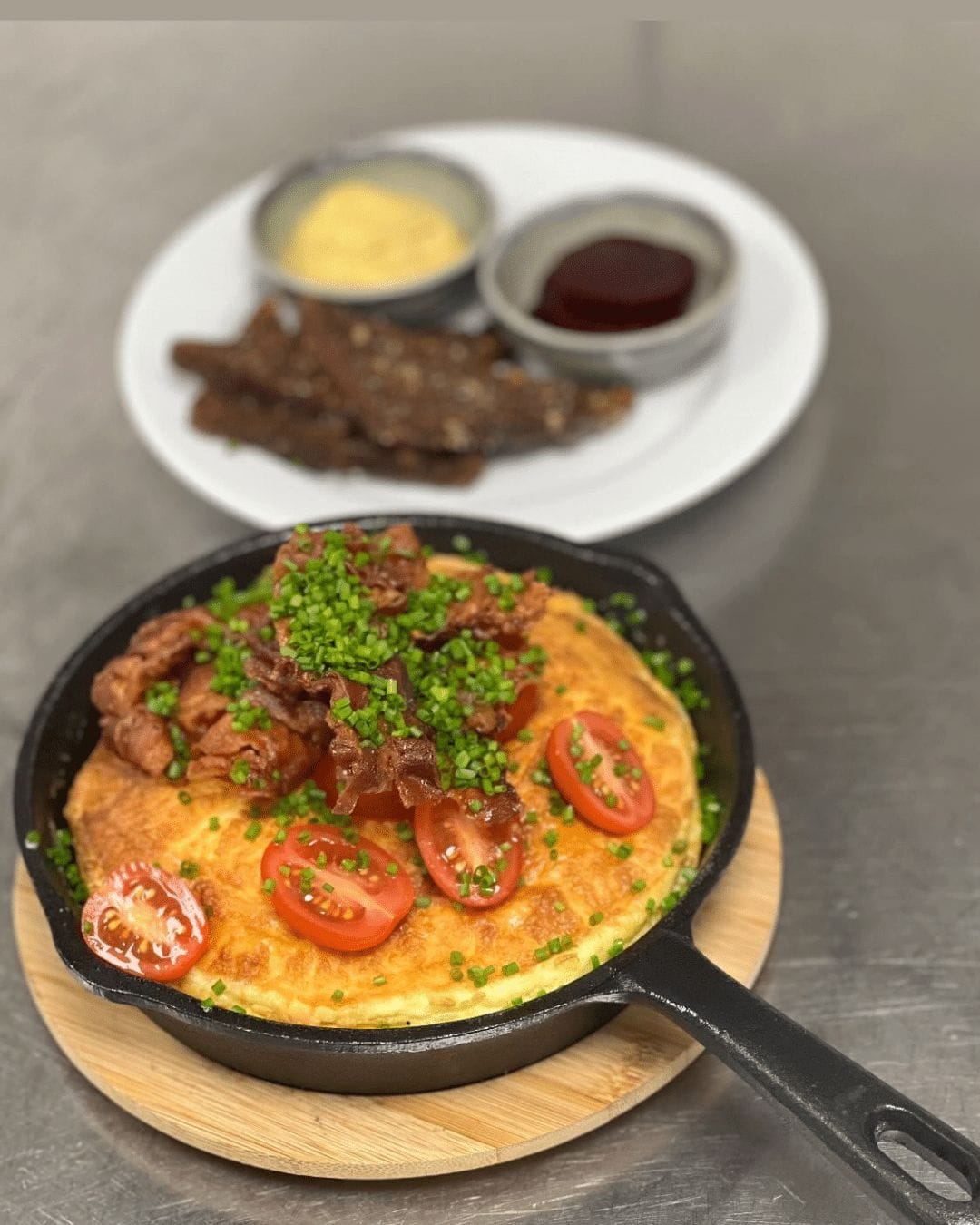 Omelet med bacon, cherrytomater og purløg i pande
