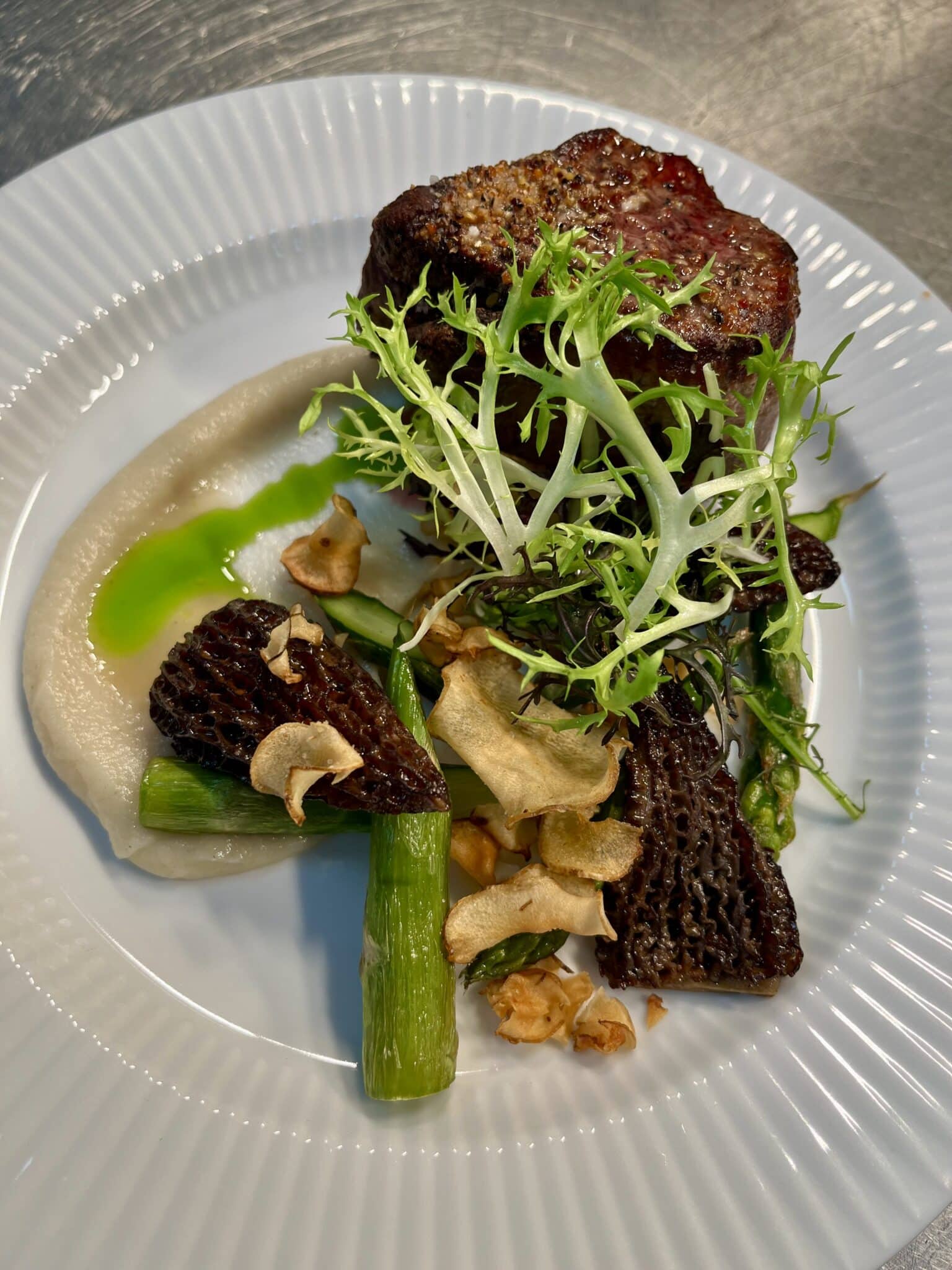 Oksemørbrad med asparges og morkler på hvid tallerken