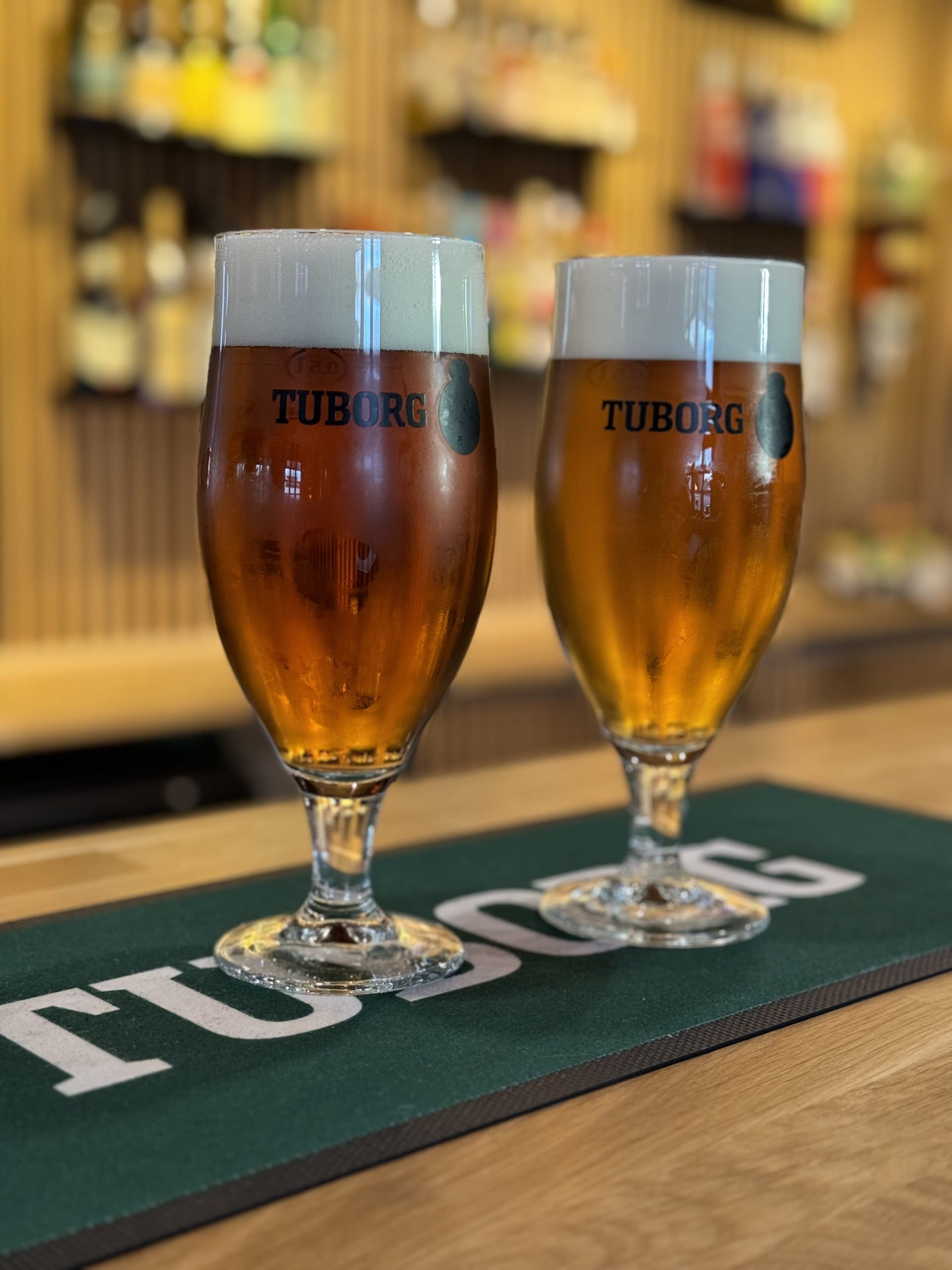 To glas øl på bar med Tuborg logo