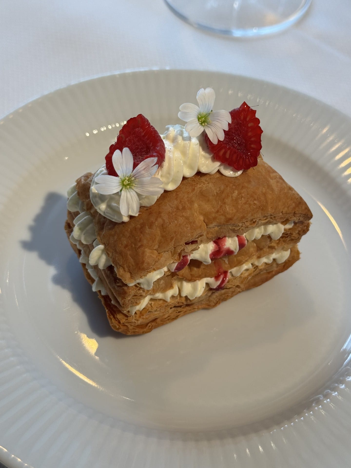 Dessert med flødeskum, hindbær og blomster på tallerken